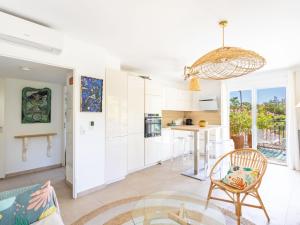 a kitchen and living room with white cabinets and a table at Apartment Le Clos Jardin-3 by Interhome in Bormes-les-Mimosas