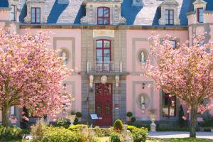 a pink house with trees in front of it at Château Hôtel Du Colombier in Saint Malo