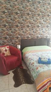 een slaapkamer met een bed en een stoel en een bakstenen muur bij Serres citycenter.Free parking place in 100m in Serres
