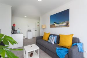 uma sala de estar com um sofá cinzento e almofadas amarelas em BeGuest Beachfront Apartment Caparica Lisbon em Costa da Caparica