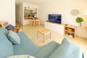 a living room with a blue couch and a tv at Los Helechos A1, central 2 bed PDC in Puerto del Carmen