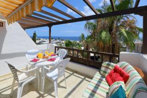 a patio with a table and chairs and the ocean at Los Helechos A1, central 2 bed PDC in Puerto del Carmen