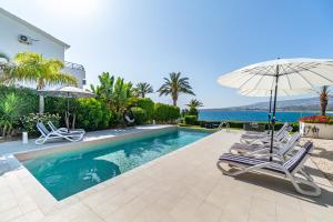 una piscina con due sedie e un ombrellone di Beach Front Villa Aqua Blu by Ezoria Villas a Coral Bay