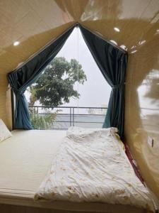 a bed in a tent with a window at Tam Đảo Xanh Homestay - Venuestay in Vĩnh Phúc