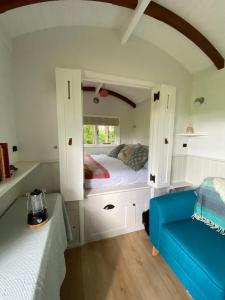a small bedroom with a bed and a blue couch at Coachroad Shepherds Huts in Petworth