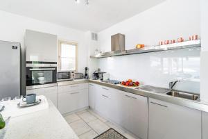 una cucina con armadietti bianchi ed elettrodomestici in acciaio inossidabile di Beach Front Villa Aqua Blu by Ezoria Villas a Coral Bay