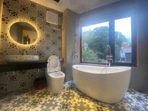 een badkamer met een bad, een toilet en een raam bij Tam Đảo Xanh Homestay - Venuestay in Vĩnh Phúc