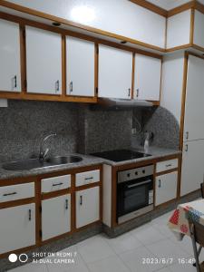 a kitchen with white cabinets and a sink at Apartamento calle Sainza 2 in Ourense