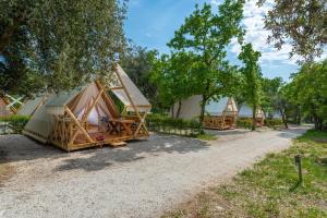 uma fila de alojamentos de turismo selvagem com árvores e uma estrada de terra batida em Eco glamping- FKK Nudist Camping Solaris em Porec
