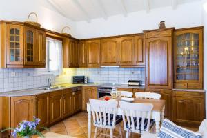 a kitchen with wooden cabinets and a table and chairs at Villa Nafsika in Ágios Stéfanos +5 photos