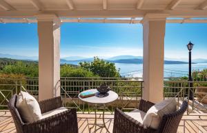 a patio with chairs and a table and a view of the water at Villa Nafsika in Ágios Stéfanos