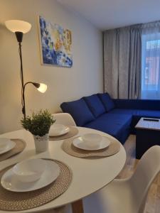 een woonkamer met een tafel en een blauwe bank bij Park Alice Apartment in Liepāja