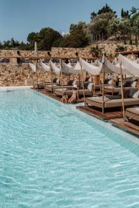 a group of lounge chairs in a swimming pool at Myra Hotel in Kavála