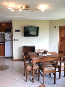 une cuisine avec une table en bois et une télévision murale dans l'établissement casa con vista y bajada al lago, à Villa Carlos Paz