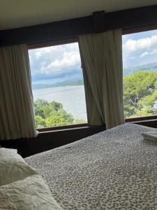 ein Schlafzimmer mit einem Bett und zwei großen Fenstern in der Unterkunft casa con vista y bajada al lago in Villa Carlos Paz