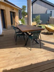 einen Holztisch und Stühle auf einer Holzterrasse in der Unterkunft Charmante villa avec studio indépendant in Vendays-Montalivet
