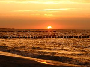 a sunset over the ocean with a pier at Urlaubs-Appartement am Dorfrand in Wieck