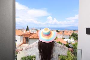 Una mujer con un sombrero colorido mirando una ciudad en Notos Premium Holiday Apartments, en Pefkohori