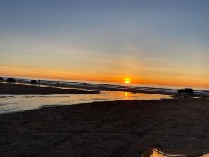 una puesta de sol en una playa con puesta de sol en Skønt hus gåafstand til tornby strand, en Hirtshals