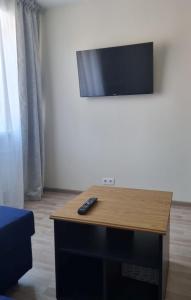 een tv aan een muur met een afstandsbediening op een tafel bij Park Alice Apartment in Liepāja