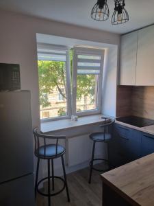 a kitchen with two bar stools in front of a window at Park Alice Apartment in Liepāja