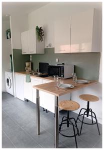 eine Küche mit einem Holztisch und 2 Hockern in der Unterkunft Studio Le Jardin in Tournon-sur-Rhône