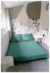 ein Schlafzimmer mit einem grünen Bett und einer Wand in der Unterkunft Studio Le Jardin in Tournon-sur-Rhône