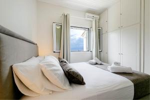 1 dormitorio con 1 cama blanca grande y ventana en Gialos Holiday House en Agia Pelagia Chlomou