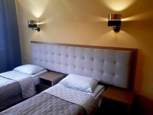 a bedroom with two beds and two lights on the wall at Hotel Ternopil in Ternopil