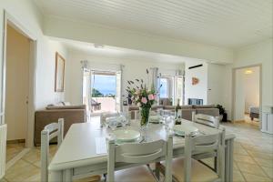 una sala da pranzo con tavolo e sedie bianchi di Gialos Holiday House ad Agia Pelagia Chlomou