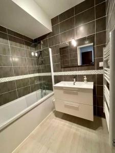 a bathroom with a sink and a tub and a mirror at Studio Le Pied à Mer in Houlgate