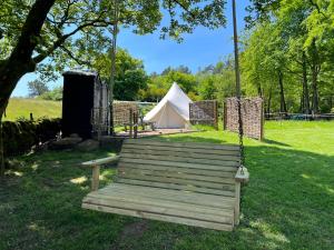 un banc à bascule dans un champ avec une tente dans l'établissement Bluebell bell tent The Roaches, à Upper Hulme