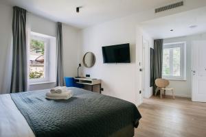een slaapkamer met een bed, een bureau en een televisie bij KALA LUXURY ROOMS by DuHomes in Dubrovnik