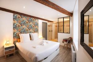 Un dormitorio con una gran cama blanca y un baño. en Le refuge de Saint-Gimer, en Carcassonne