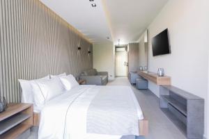 ein Schlafzimmer mit einem großen weißen Bett und einem TV in der Unterkunft Notos Premium Holiday Apartments in Pefkohori