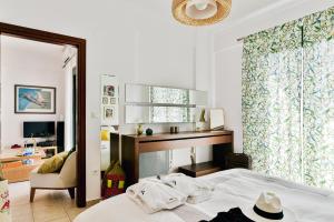 um quarto com uma cama, uma cadeira e um espelho em Oliva Holiday Homes em Dhiyeliótika