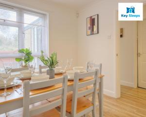 ピーターバラにあるFour Bedroom By Keysleeps Short Lets Peterborough With Free Parking Spacious Central Contractorのテーブルと椅子と窓のあるダイニングルーム