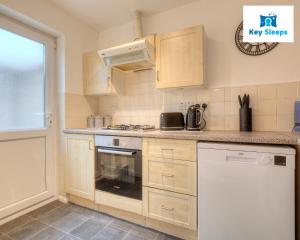 a kitchen with a stove top oven next to a window at Four Bedroom By Keysleeps Short Lets Peterborough With Free Parking Spacious Central Contractor in Peterborough