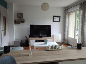 een woonkamer met een flatscreen-tv en een tafel bij Appartement Cocooning in Ars-sur-Moselle