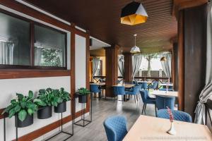 a restaurant with blue chairs and tables and plants at Zagorod Hotel in Girka Polonka