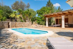 a swimming pool in a backyard with a stone wall at Finca Biniali in Sencelles