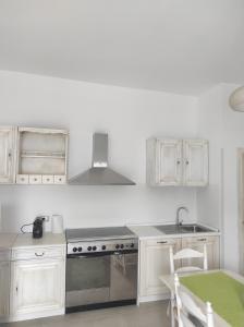 - une cuisine blanche avec cuisinière et évier dans l'établissement Deluxe Family Suite, à San Menaio