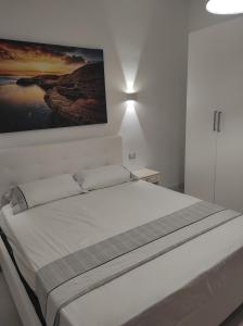 a white bedroom with a bed with a painting on the wall at Deluxe Family Suite in San Menaio
