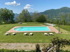 a swimming pool with lounge chairs in a field at Agriturismo Il Serrino in San Marcello Pistoiese