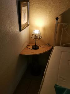 una lámpara sentada en una mesa junto a una cama en Le P'tit gîte en Saint-Privat