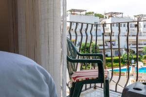una sedia verde seduta su un balcone con vista sulla piscina di HomeForGuest Bright studio in La Carihuela near the beach a Torremolinos
