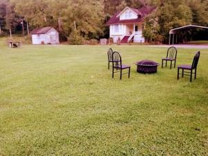 quatro cadeiras e uma mesa num campo em Sandy’s house 