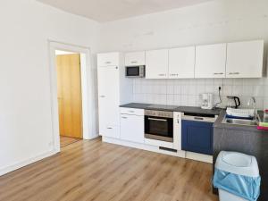 La cuisine est équipée de placards blancs et de plaques de cuisson bleues. dans l'établissement Work & Stay Apartments in Leverkusen, à Leverkusen