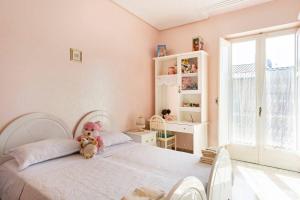 a white bedroom with a teddy bear sitting on a bed at Alloggio incantevole: Licata in Licata