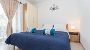 a bedroom with a blue bed with a window at Apartments Memories in Baška